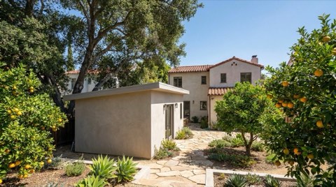 A small modern ADU guest house tucked behind a Spanish revival home in a tree-shaded Los Feliz backyard