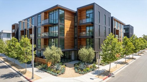 A contemporary condo building in a master-planned Playa Vista community with wood and metal accent panels, small balconies, and a landscaped entrance on a tree-lined street