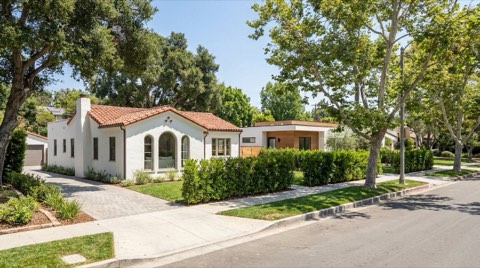 A 1930s Spanish-style single-family home in Westwood with a small modern ADU guest house visible behind a low hedge in the side yard