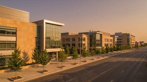 A generic museum-row streetscape with modern stone and glass institutional building facades in warm late-afternoon light