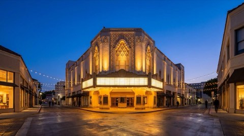 A historic Art Deco theater facade in Westwood Village lit up at dusk along a walkable street with string lights