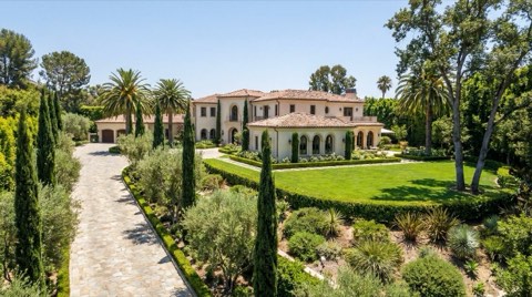 A grand Bel Air estate with a long paved driveway, manicured lawn, and understated Mediterranean architecture