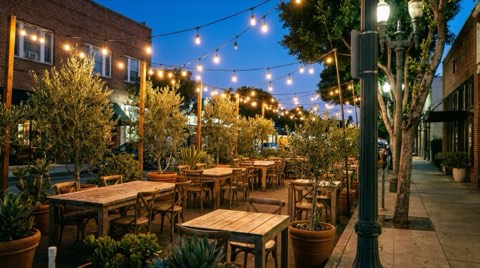 An empty outdoor restaurant patio strung with lights on a Culver City street at dusk.