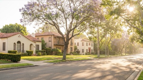 A quiet, tree-lined Westwood residential street in soft morning light showing a mix of Spanish-style and Mediterranean-style homes
