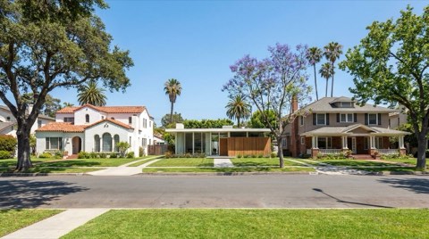 A residential street showing a mix of Spanish colonial, mid-century modern, and traditional home styles side by side