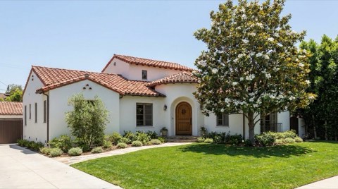 A white stucco Spanish revival home in Los Feliz with a red tile roof and a mature magnolia tree on the front lawn