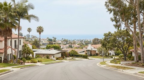 A residential street on a Mar Vista hillside with a distant ocean view beyond the rooftops
