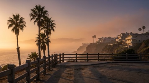 A scenic Santa Monica coastal bluff overlook with a guardrail above the Pacific Ocean at sunset