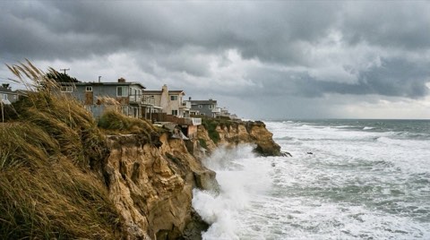A dramatic coastal bluff in Venice with beach houses under an overcast sky