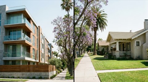 A streetscape showing a modern condominium building alongside a classic single-family home with a lawn