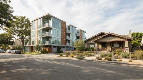 A Culver City street contrasting a modern condominium building with a single-family craftsman home.