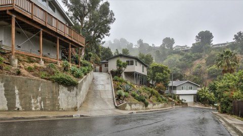 A hillside street in Studio City on an overcast morning with homes built on sloped lots and retaining walls