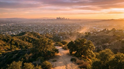 A golden hour view from a Studio City hillside overlook across the San Fernando Valley toward the distant downtown Los Angeles skyline