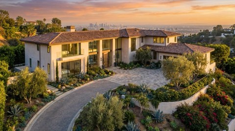 A well-maintained Hollywood Hills estate at golden hour with warm afternoon light on its facade and a long driveway leading up to the entrance