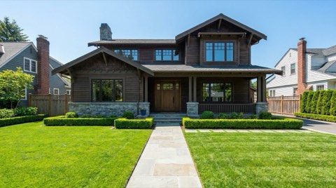 A staged single-family home exterior with a manicured lawn and trimmed hedges in bright daylight