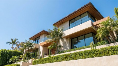 An upward-angle view of an elegant home facade and rooftop against a clear sky