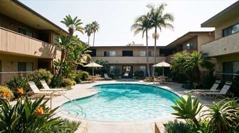 A 1970s low-rise Los Feliz condominium courtyard with a swimming pool and landscaped greenery at midday