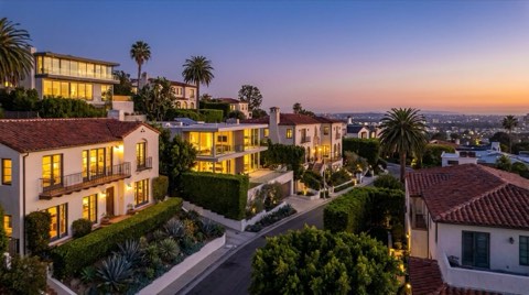 A row of upscale Los Feliz hillside homes glowing with warm interior light at dusk