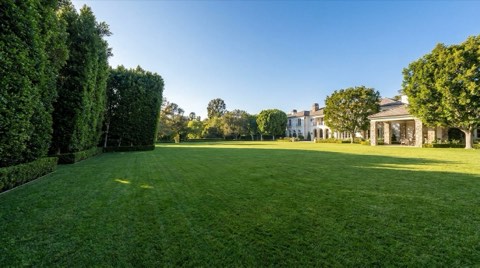 An expansive manicured lawn on a large Bel Air estate lot bordered by tall clipped hedges