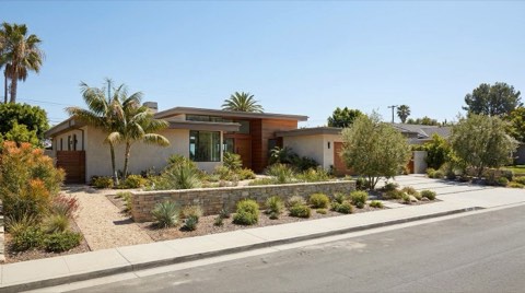 A wide single-family lot with generous side-yard setback space and a low retaining wall.