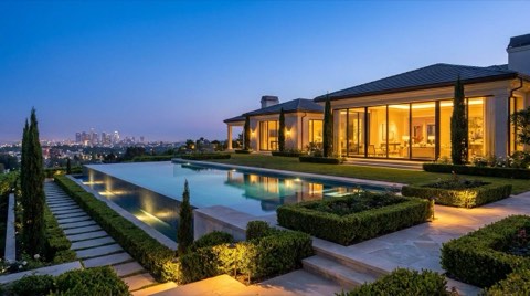 A luxury Los Feliz estate with an infinity pool and glass walls overlooking distant city lights at dusk