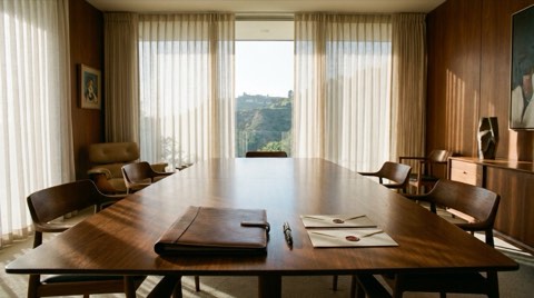 A polished table with a closed document folder, fountain pen, and two sealed envelopes in soft afternoon light