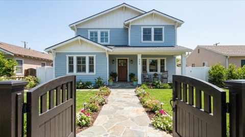 A bright, clean single-family home staged for a showing with an open front gate and tidy walkway in midday light