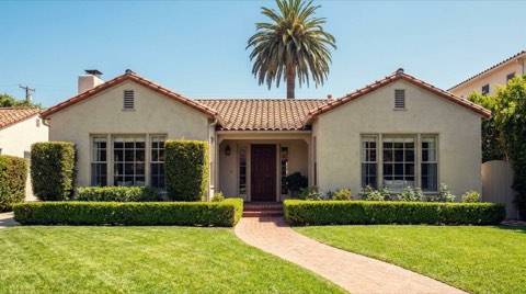 A well-maintained 1930s traditional single-family home in Westwood with a manicured lawn and brick walkway, photographed in bright midday sun to convey move-in-ready curb appeal