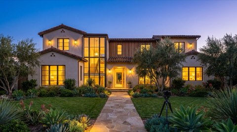 A home exterior lit at twilight with warm glowing windows against a blue-hour sky