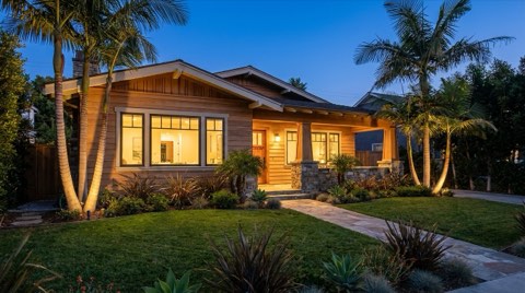 A professionally staged Santa Monica home exterior glowing with warm window light at twilight, ready for an open house