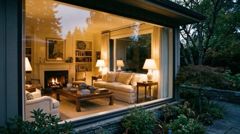 A beautifully staged living room interior seen through a large picture window at dusk.