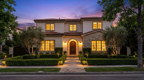 An elegant Westwood single-family home photographed at twilight with warm interior lights glowing and landscape lighting on the front garden, styled as a polished real estate marketing shot