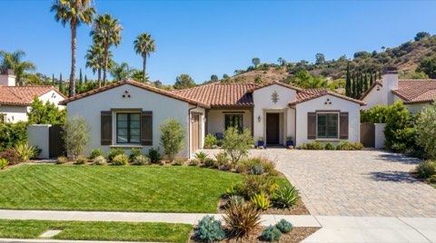 An upscale single-family home exterior with well-maintained landscaping in bright clear daylight