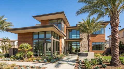 A larger upscale modern townhome exterior with big windows and refined landscaping, suggesting a spacious step-up home in bright daylight.