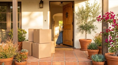 Stacked cardboard moving boxes on the front porch of a Spanish style home in Los Feliz at morning