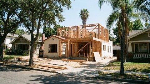 Wooden framing of a new home addition on an established lot surrounded by mature trees.
