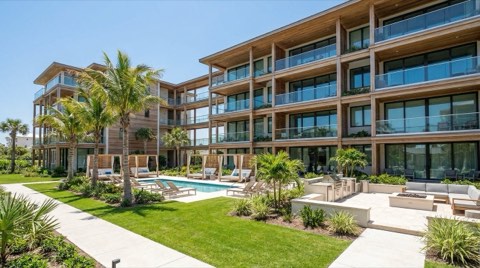 A modern condominium building with a shared courtyard and pool area under palm trees