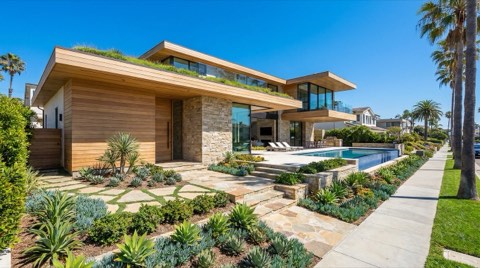 An upscale single-family home with manicured landscaping under a clear blue sky