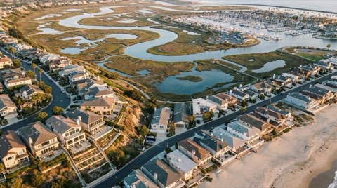 An elevated panoramic view showing a hillside section, flats, wetlands, and marina of a coastal neighborhood