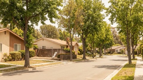A suburban residential street in Studio City with a playground glimpsed near homes at midday