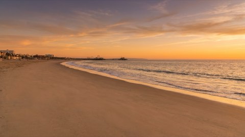 Wide sandy Santa Monica beach at golden hour with the coastline curving north and no people in view