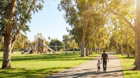 A sunny, tree-lined park in Santa Monica with a distant parent and child walking on a path