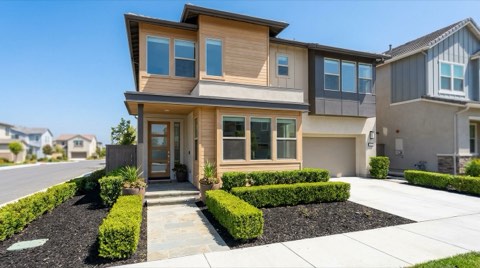 A pristine modern townhome exterior with manicured landscaping, staged for sale under bright inviting daylight.
