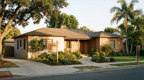 A traditional 1950s California ranch-style home exterior in Santa Monica with a blank yard sign at sunset
