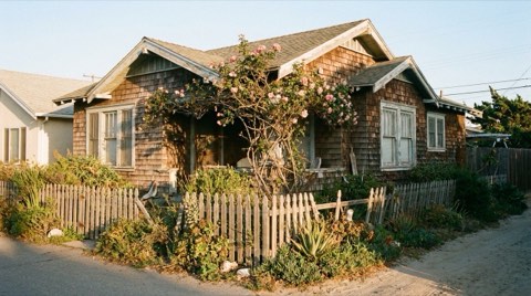 A vintage 1930s Venice beach bungalow with weathered wood shingles and a climbing rose