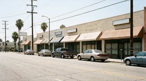 A small retail strip along a boulevard near Beverlywood with low-rise storefronts in bright daylight
