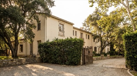 An older Bel Air estate with faded paint, an overgrown hedge, and a weathered wooden gate hinting at untapped potential