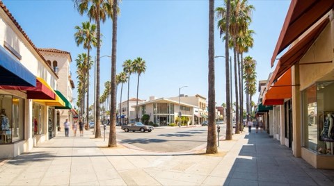A bright iconic corner of Ventura Boulevard in Studio City at midday with palm trees and storefront awnings