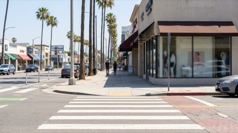 A pedestrian sidewalk along Ventura Boulevard in Studio City with a marked crosswalk and bike lane at midday