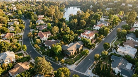 A small-town-feeling residential neighborhood with a distant glimpse of a private lake through trees at late afternoon.